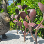 一株株銅葉舒展枝姿，在陽光下閃耀生命的光澤，鳥兒靜靜守望，為街道增添自然的詩意。
