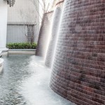 與接待大廳相對，僅隔一道玻璃落地窗即為「戶外水瀑牆」。流水潺潺與磚石沖刷出平整的紋路，水光相映下霧氣生騰，彷若仙境。－【新業(yè)觀峰】。