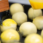 刷上蛋黃液，點(diǎn)上芝麻裝飾，圓潤蓬鬆的蛋黃酥即將穿上金黃酥脆的外衣。