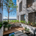 四季合院，每三層設(shè)計(jì)一處公共大露臺(tái)，從梯廳走入彷彿大家庭的合院(埕)，提供住戶們休憩及交誼空間，搭配四季主題的呼應(yīng)，此為七樓的夏季-種植小花紫薇與厚葉石斑木。