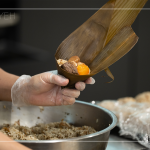 將粽葉三分之一處折起，交叉形成漏斗狀，轉(zhuǎn)著處末端折一個折角，再將內(nèi)餡包入。