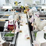 新業(yè)同仁與甘霖志工們分工合作，以生產(chǎn)線的方式有序地進行，將熱騰騰的餐食迅速裝盒，確保長輩能準時享用午餐。